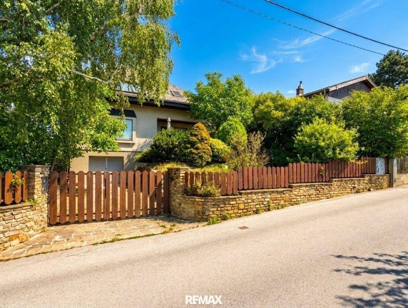 Außenansicht des Hauses von der Straße aus mit gepflegtem Vorgarten und Holzzaun.