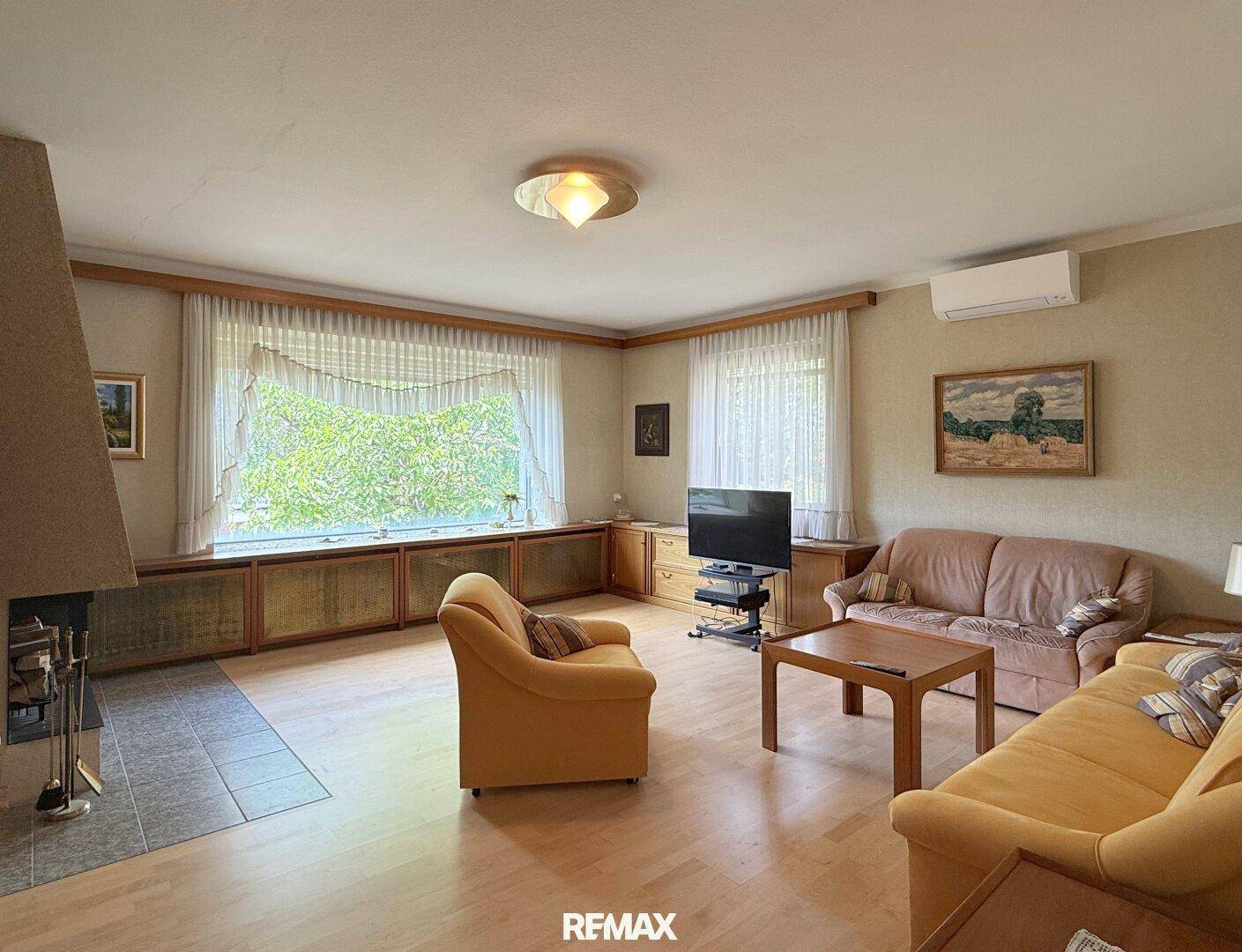 Geräumiges Wohnzimmer mit Klimaanlage, großem Fenster und traditioneller Einrichtung.