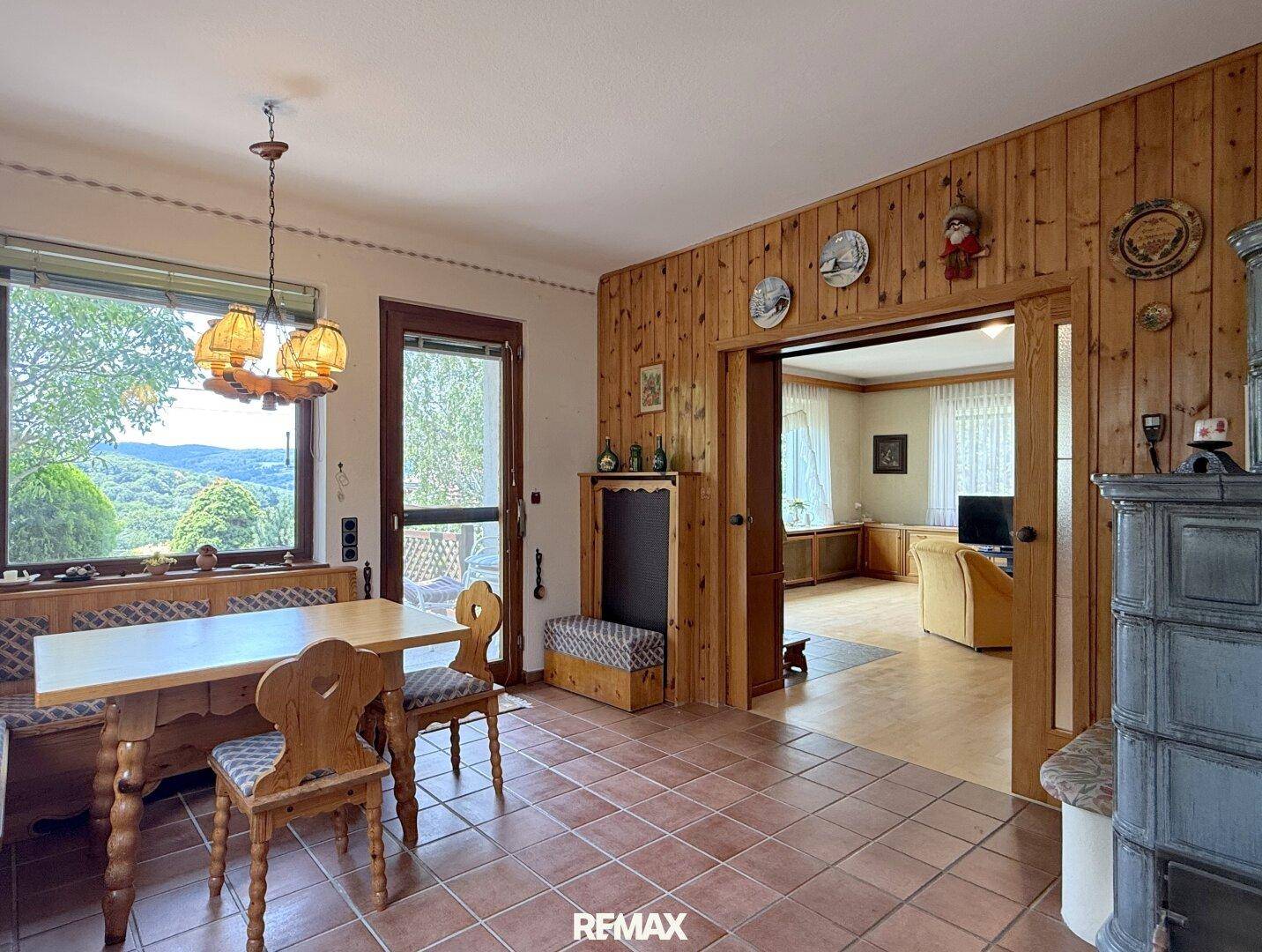 Essbereich mit traditionellem Holztisch, Kachelofen und Zugang zur Terrasse mit Weitblick.