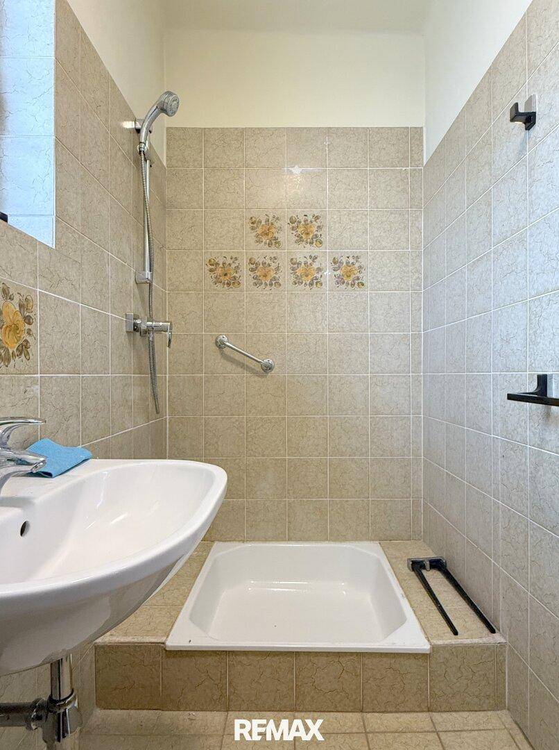 Kleines Badezimmer mit Dusche, Waschbecken und beigen Fliesen im traditionellen Stil.