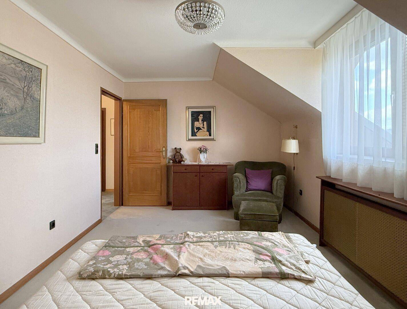 Schlafzimmer im Dachgeschoss mit Schräge, Fenster und traditioneller Einrichtung.