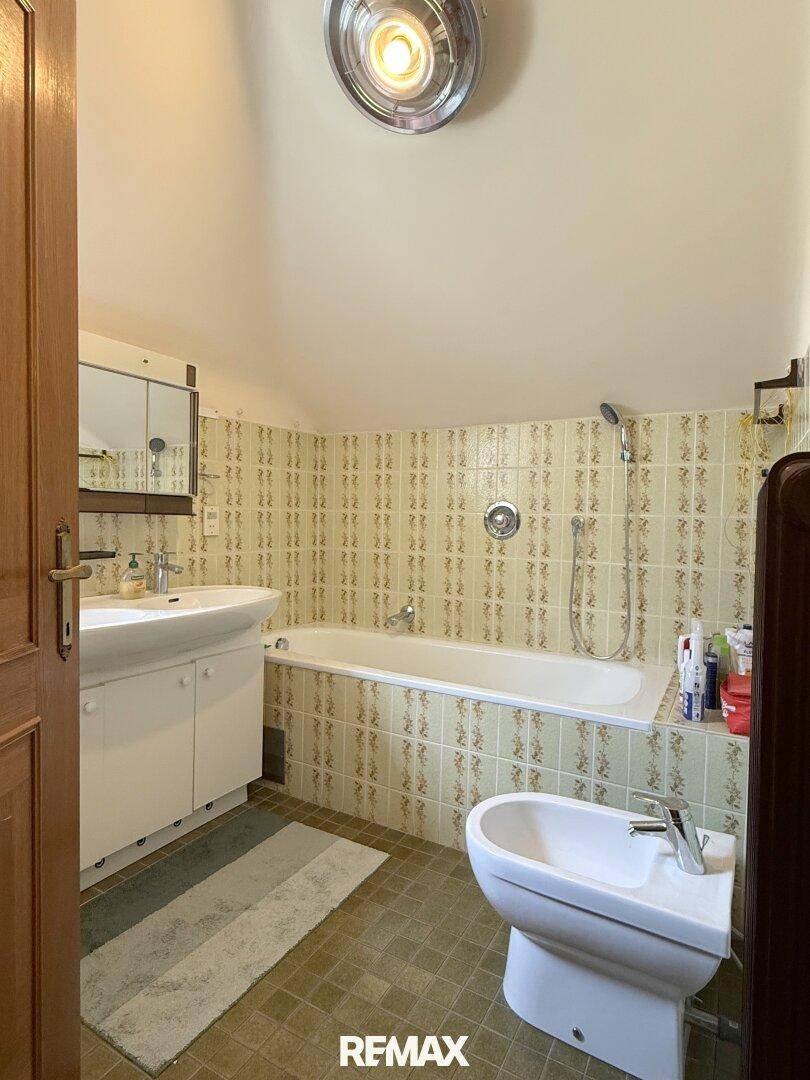 Badezimmer im Dachgeschoss mit Badewanne, Bidet und traditionellen Fliesen.