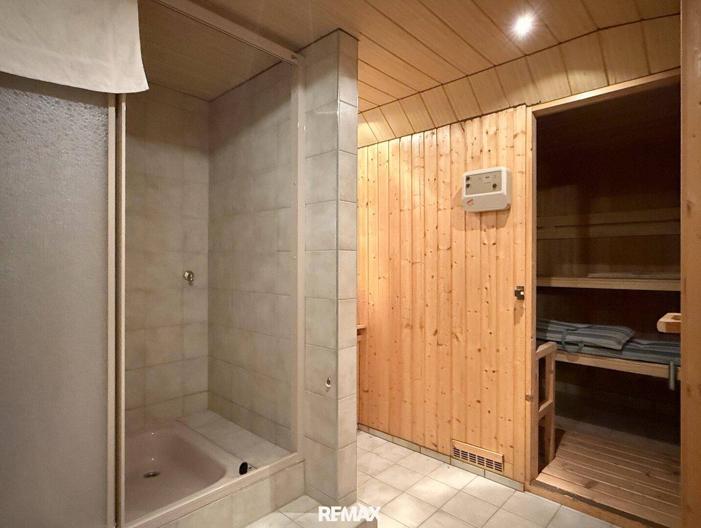 Wellnessbereich im Keller mit Sauna, Dusche und Fliesenboden.