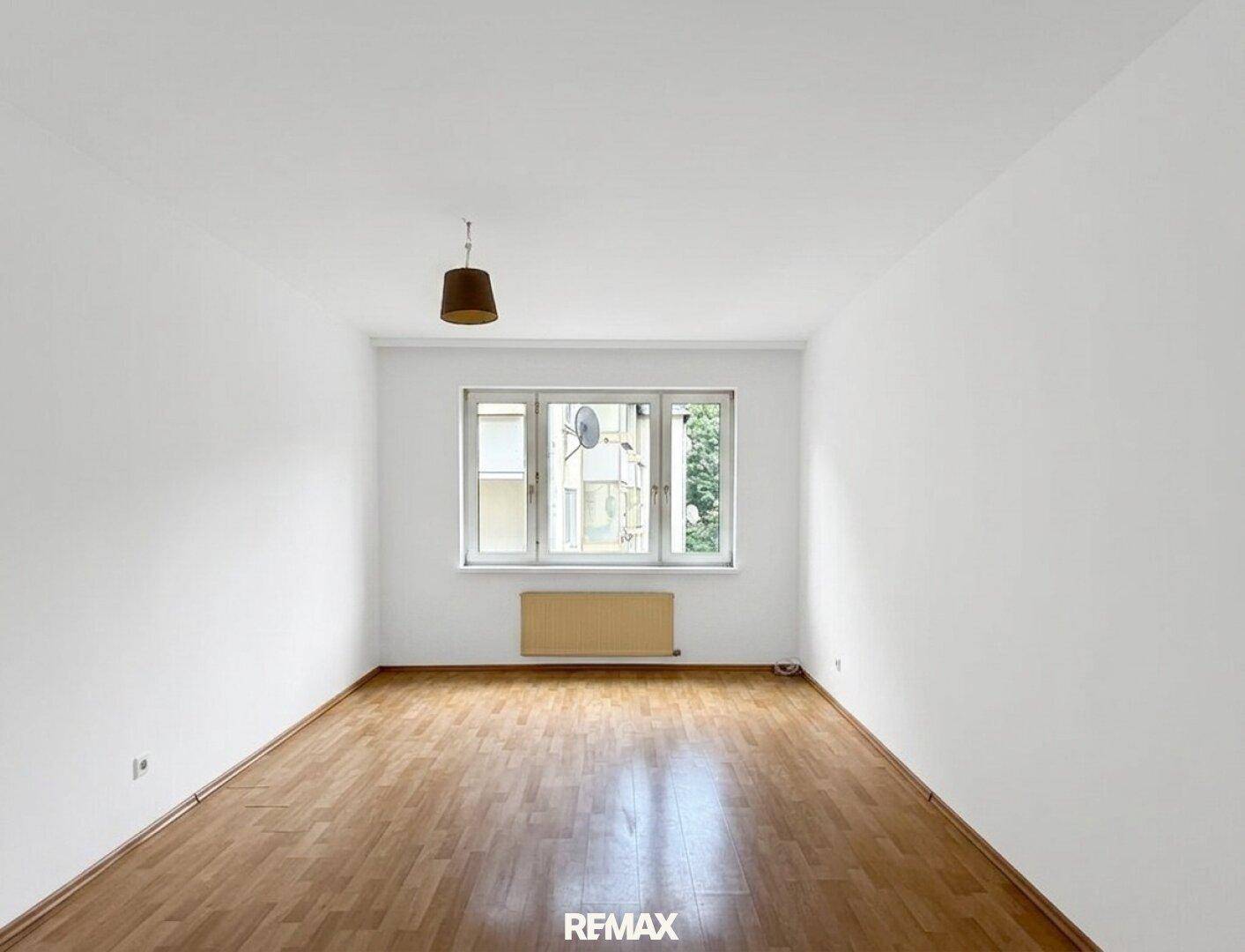 Freundliches Schlafzimmer mit Holzfußboden, großen Fenstern und viel Tageslicht für eine angenehme Atmosphäre.