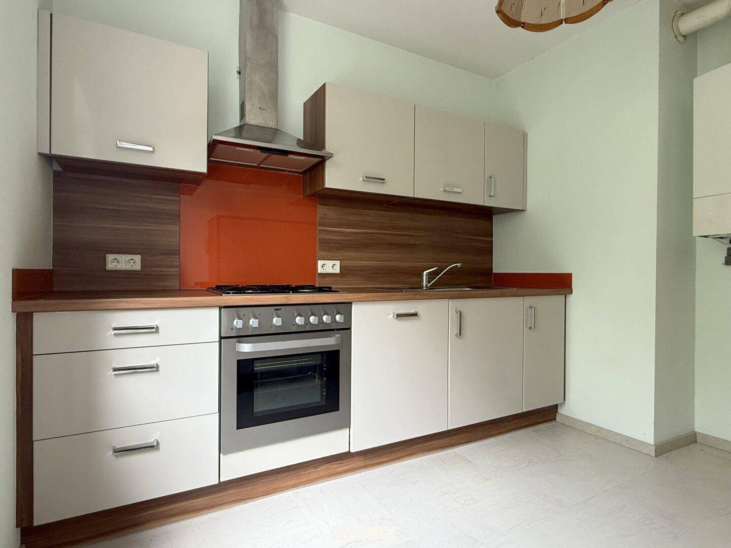Funktionale Einbauküche mit Herd, Backofen und Dunstabzugshaube in hellem Design, gut ausgestattet.