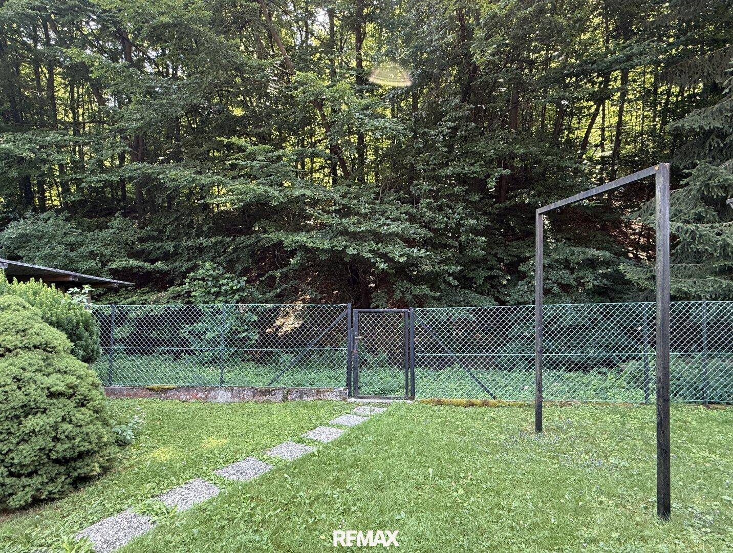 Hinterer Gartenbereich mit Zaun und üppiger Vegetation, bietet Privatsphäre.
