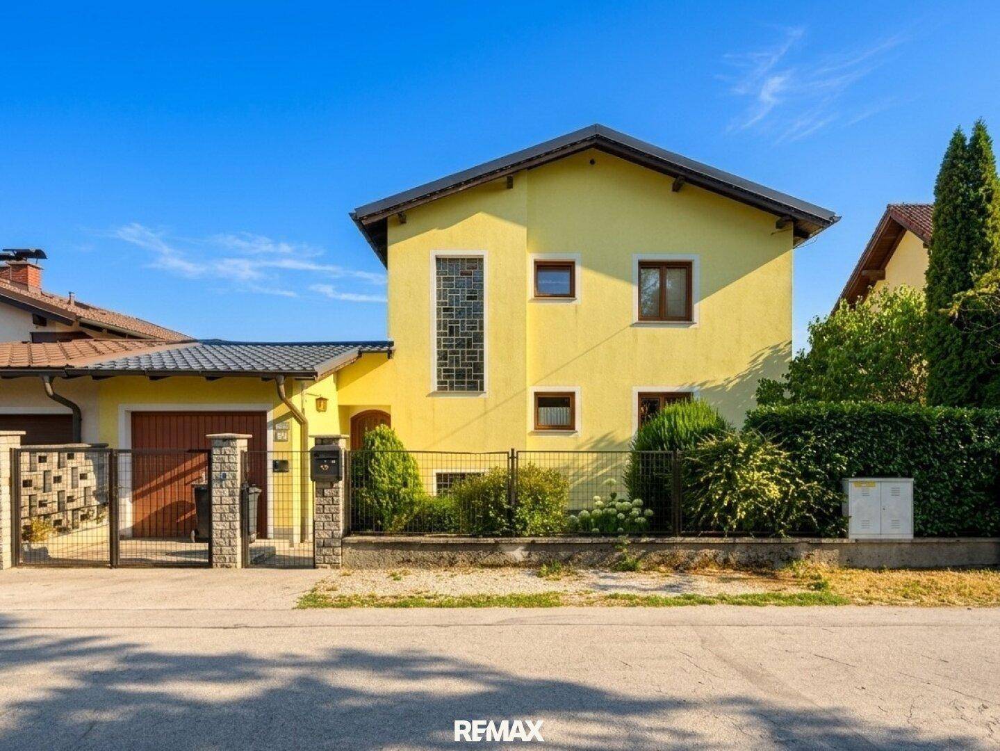 Vorderansicht des gelben Einfamilienhauses mit Garage und Vorgarten.