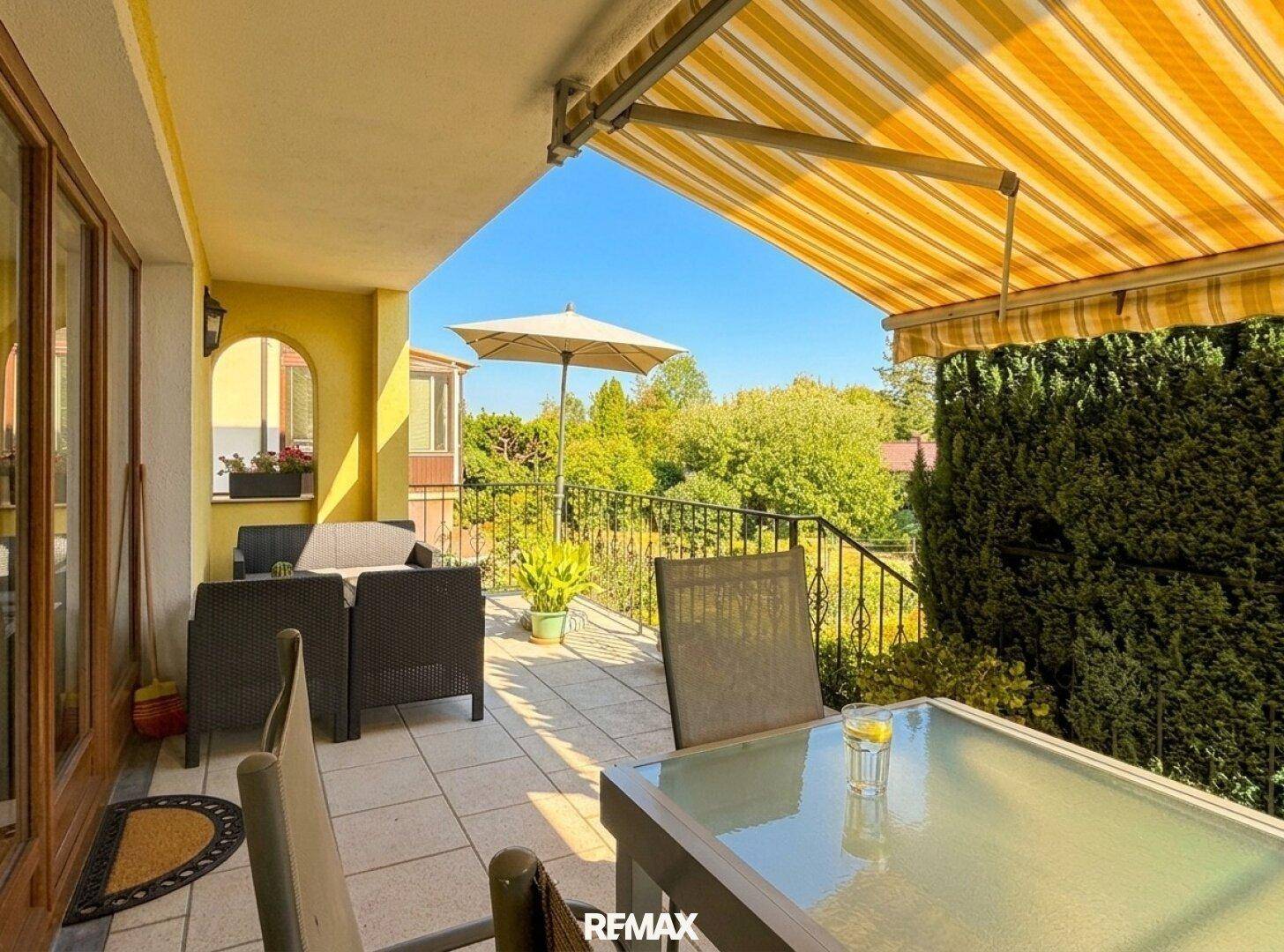 Geräumige Terrasse mit Esstisch, Sonnenschirm und weitem Blick in die Natur.