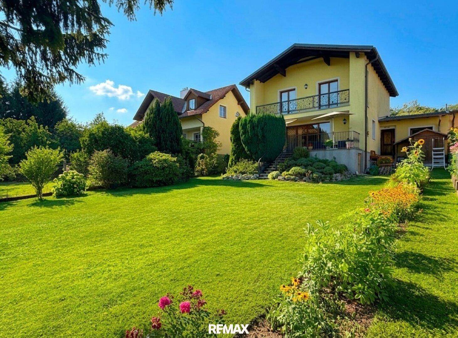 Weitläufiger Garten mit Rasenfläche und Blick auf das gelbe Einfamilienhaus.