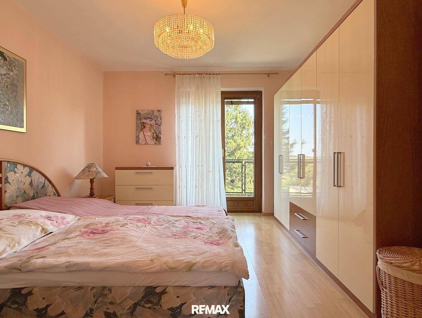 Schlafzimmer mit Doppelbett, Einbauschränken und Zugang zum Balkon.