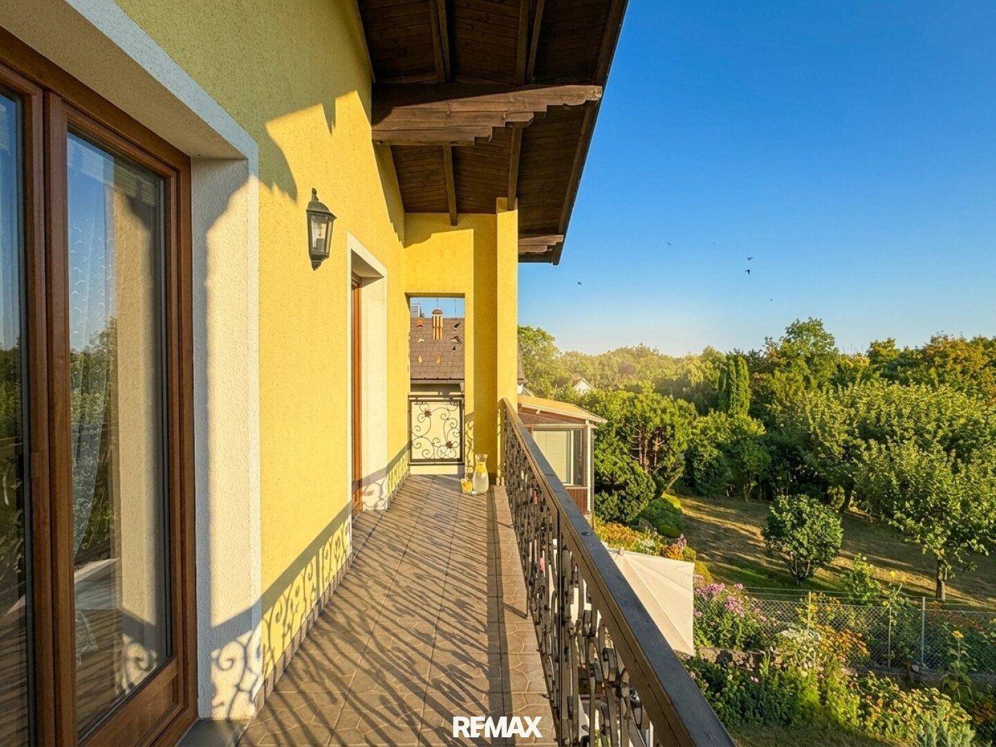 Langer Balkon mit schmiedeeisernem Geländer und weitem Blick ins Grüne.
