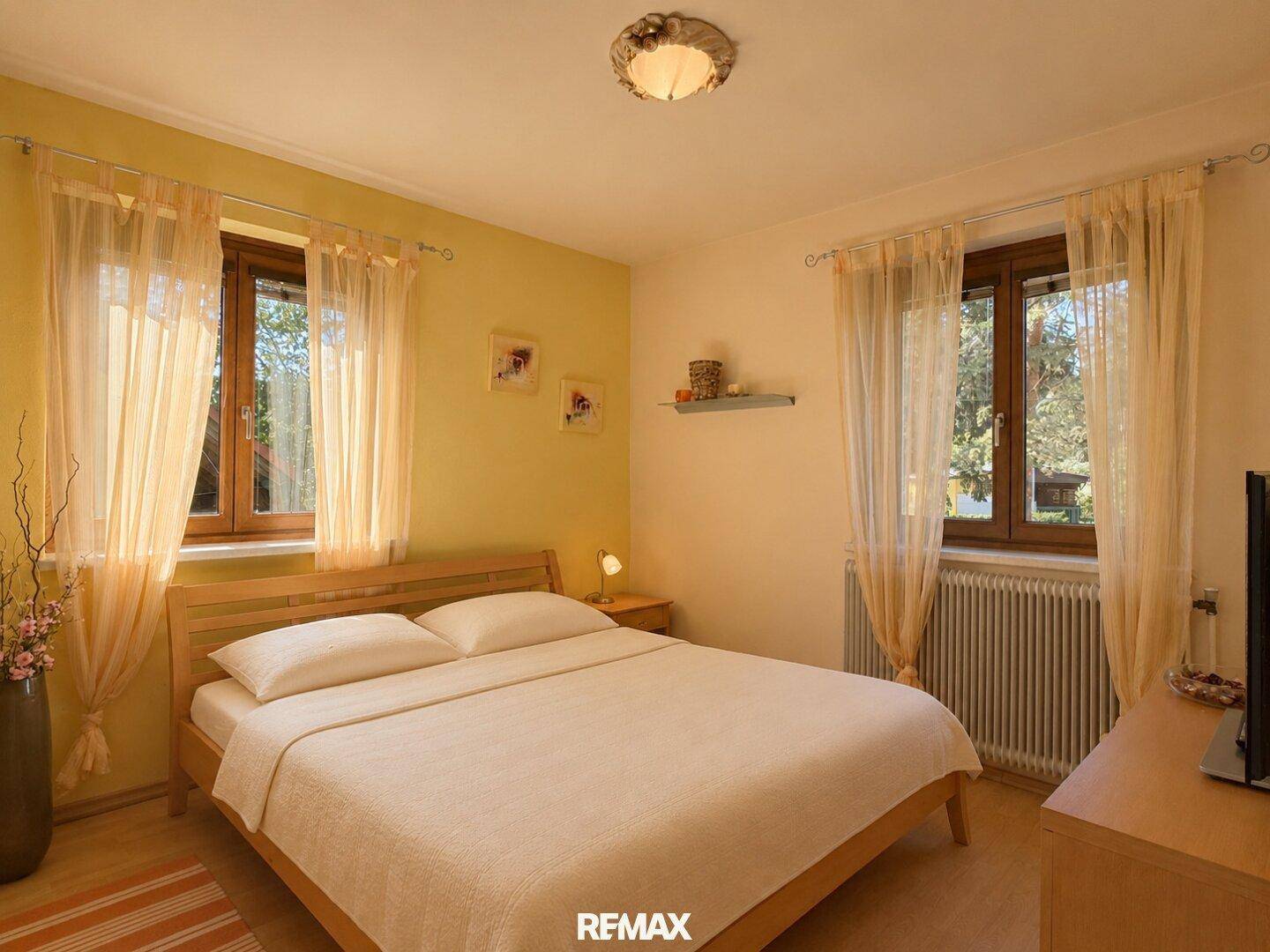 Gemütliches Schlafzimmer mit zwei Fenstern und Blick in den Garten.