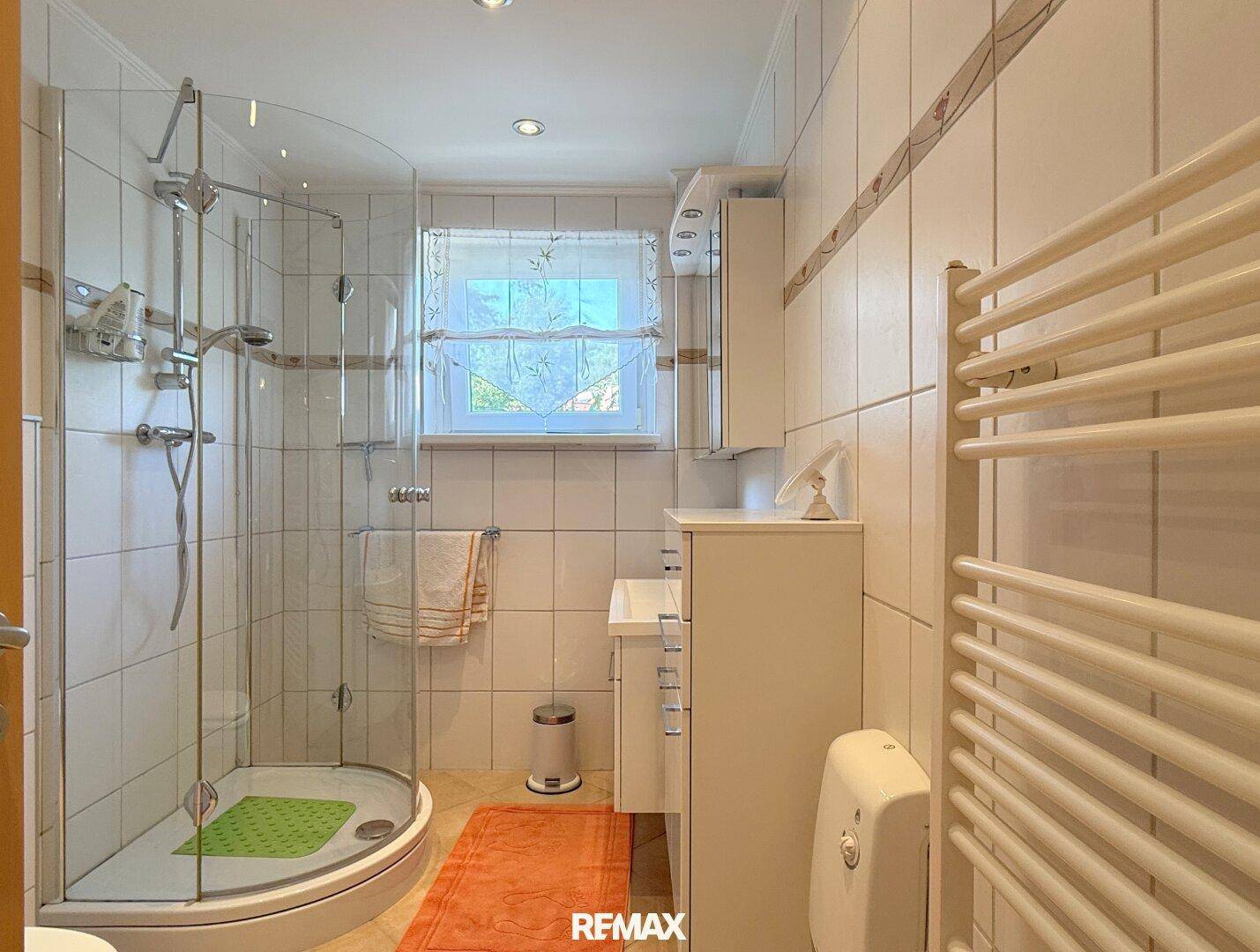 Modernes Badezimmer mit Duschkabine, Waschbecken und Handtuchheizkörper.