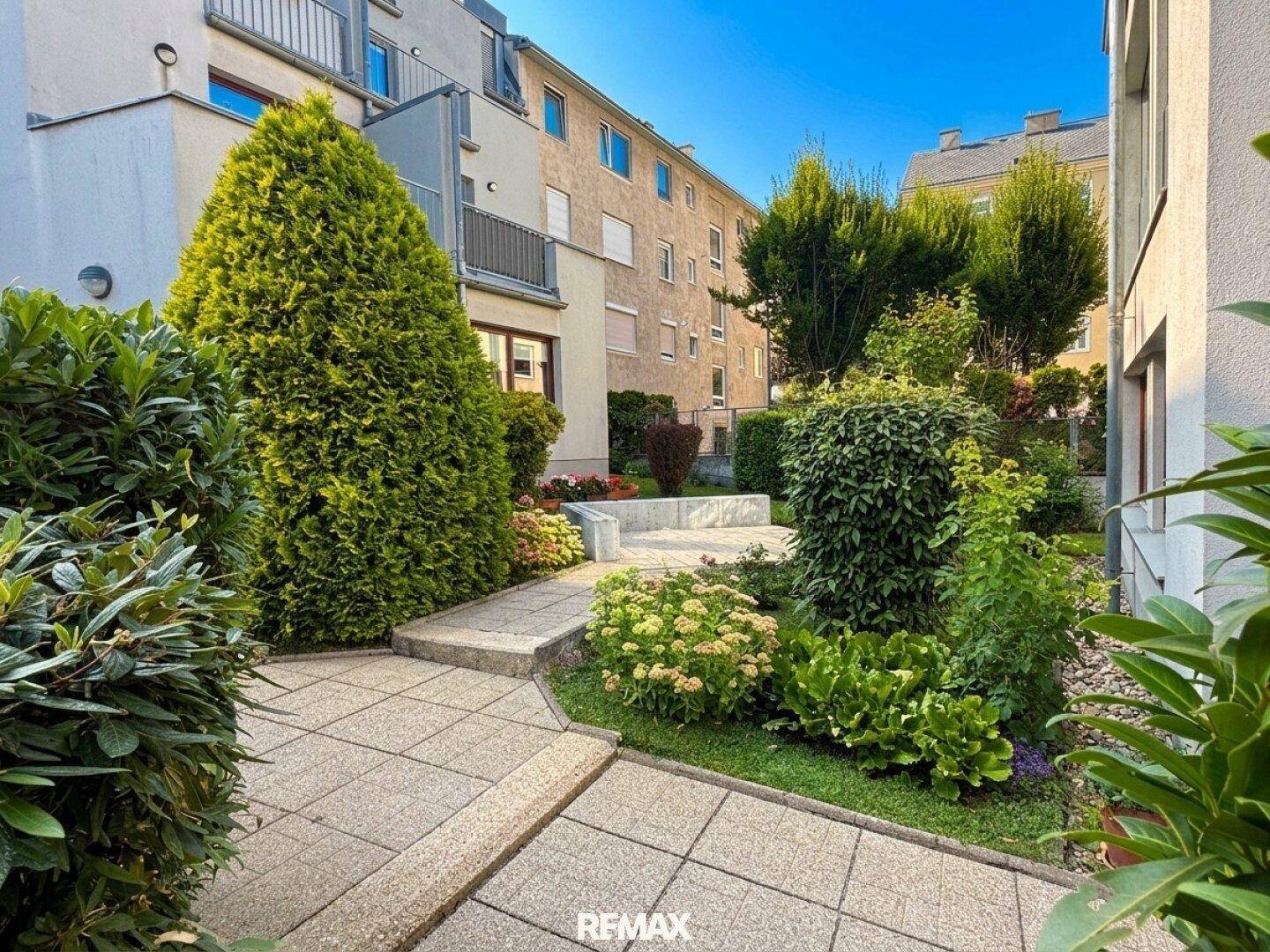 Gepflegter Gartenweg mit Stufen, umgeben von üppigem Grün und Sträuchern.