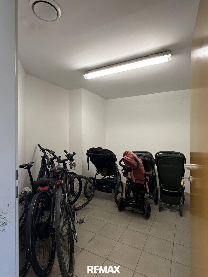 Gemeinschaftlicher Abstellraum für Fahrräder und Kinderwagen mit Fliesenboden.