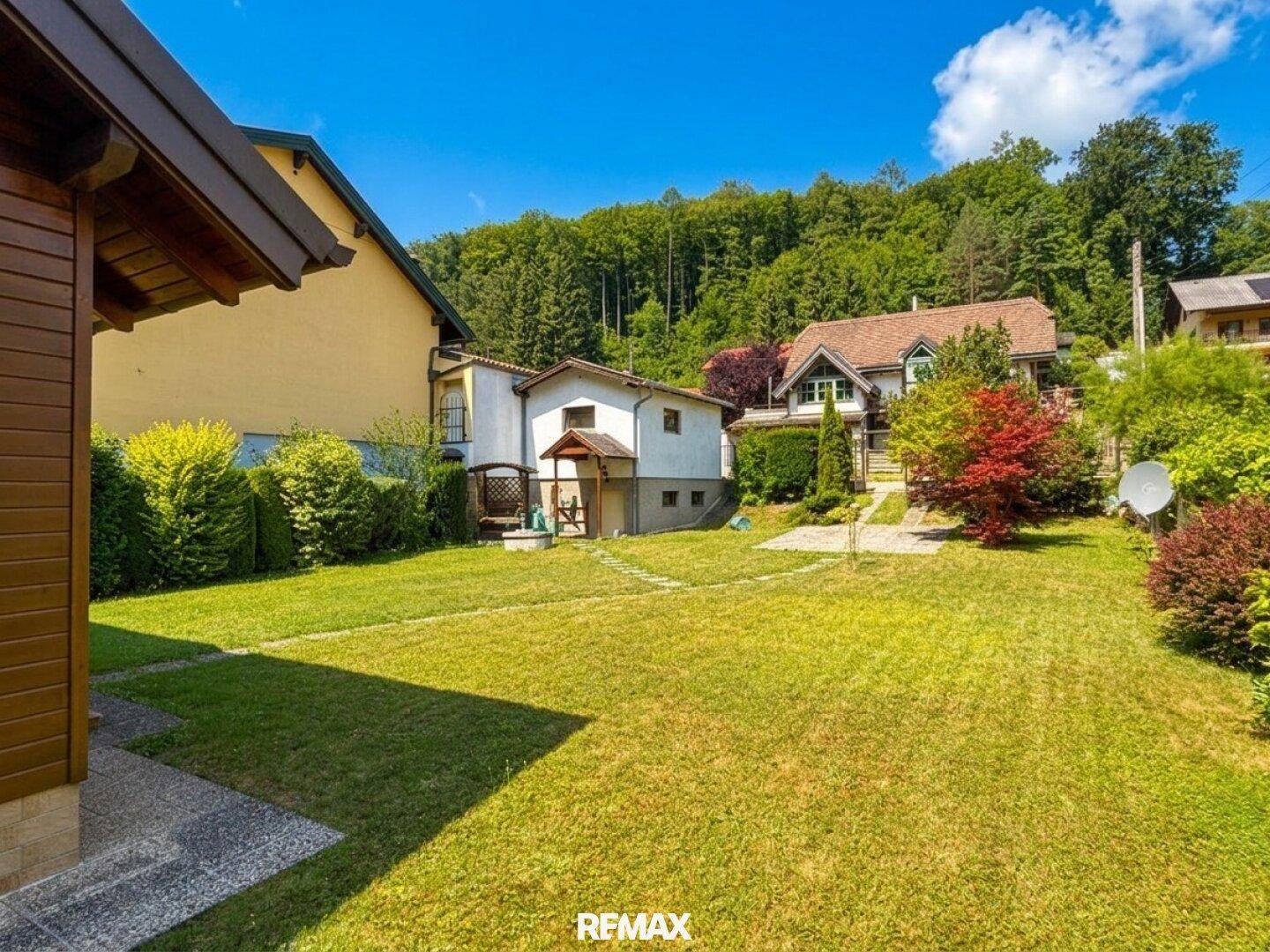 Weitläufiger Garten mit Rasen und Blick auf das charmante Holzhaus und die Umgebung.