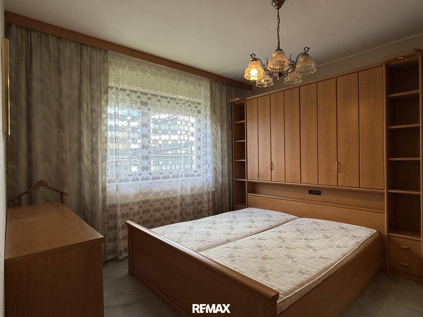 Schlafzimmer mit Doppelbett, Holzschrank und Teppichboden in traditionellem Stil.