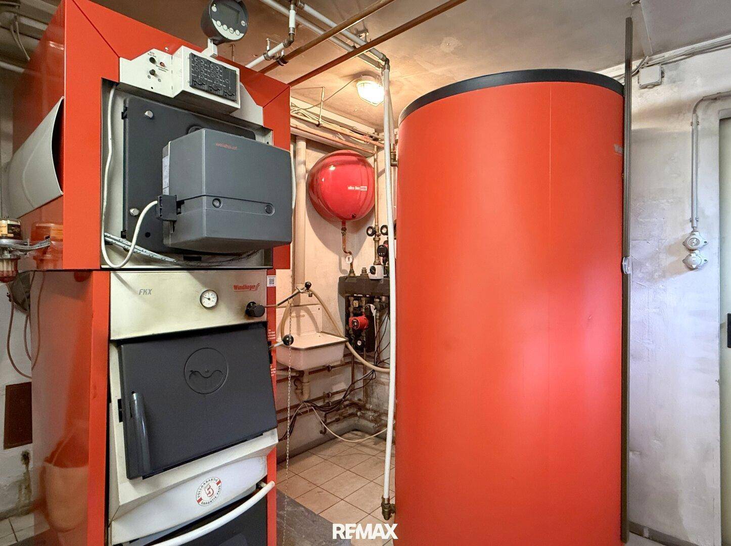 Heizungsraum im Keller mit großem Heizkessel und Warmwasserspeicher.