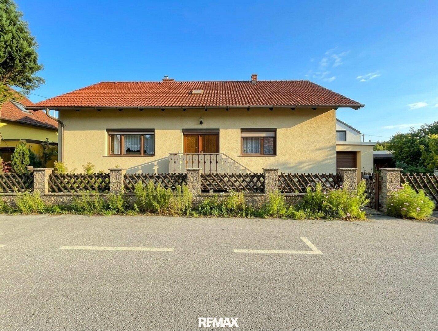 Ansicht des Einfamilienhauses von der Straße mit gepflegtem Vorgarten und sonnigem Wetter.