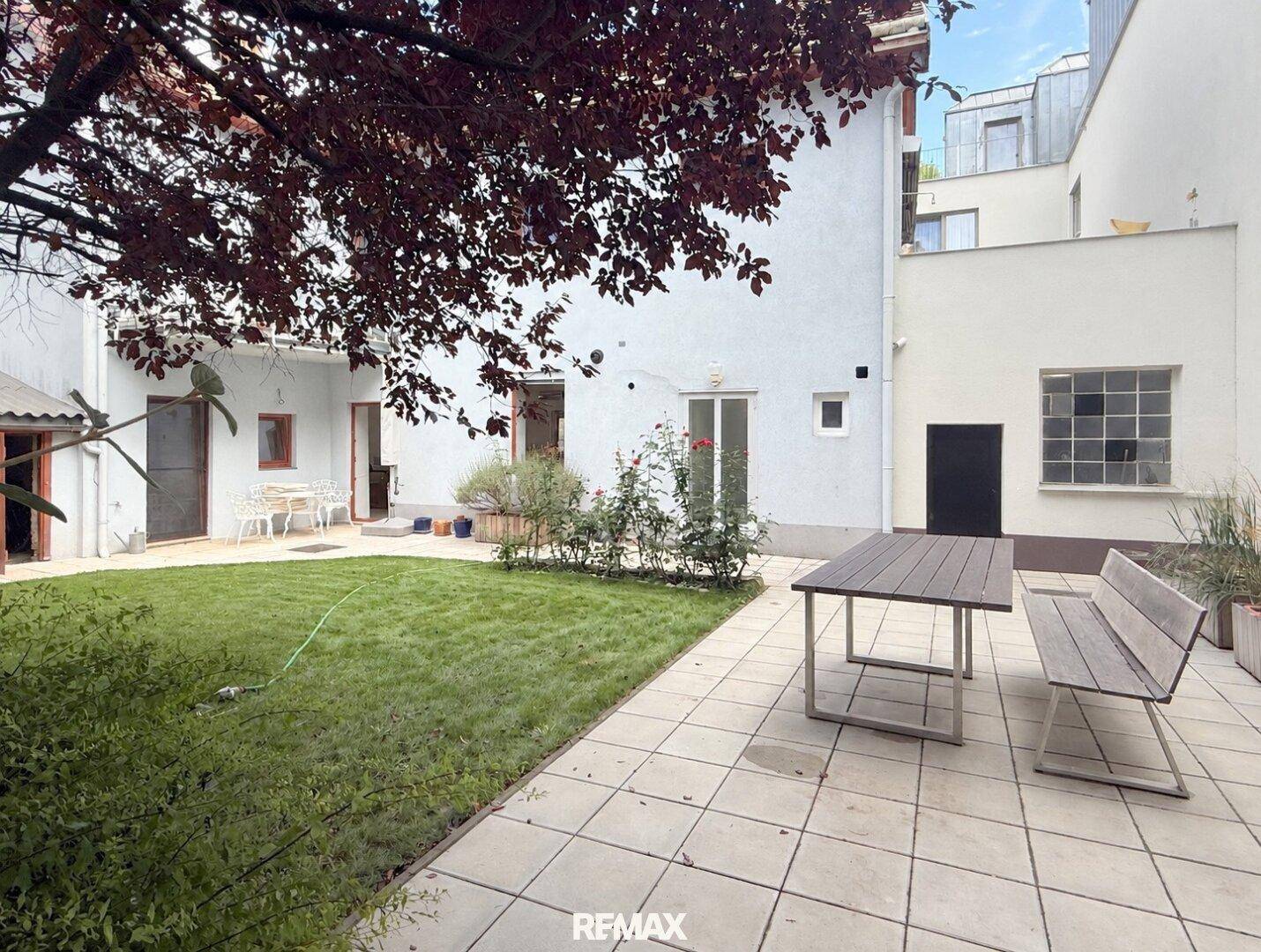 Geräumige Terrasse im Garten mit Esstisch und Sitzbank, umgeben von Grünflächen.