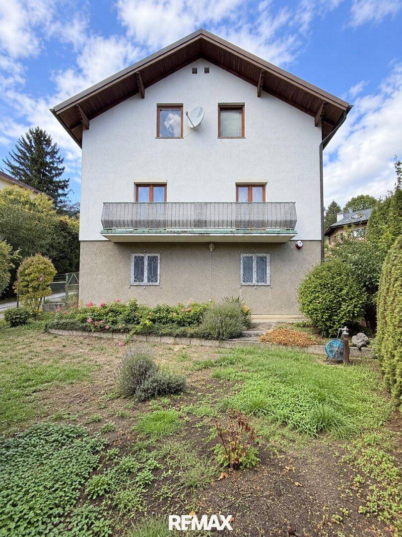 Vorderansicht des Hauses mit Gartenbereich und einem Balkon im Obergeschoss.