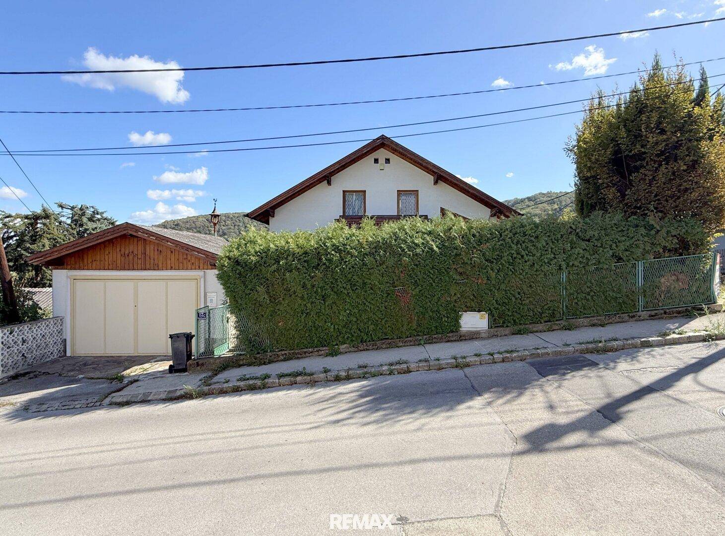 Ansicht des Hauses von der Straße mit Garage und einer hohen Hecke als Sichtschutz.