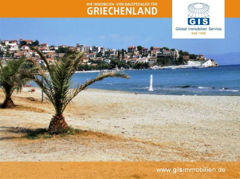 Sandstrand mit Palmen und malerischer Küstenstadt im Hintergrund unter blauem Himmel.