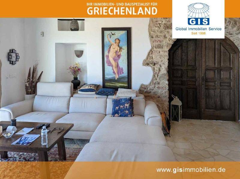 Komfortables Wohnzimmer mit großer Couch, rustikalen Steinwänden und massiven Holztüren.