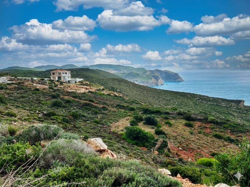 Ein modernes Haus auf einem grünen Hügel mit weitem Blick auf das Meer und die Küstenlandschaft.