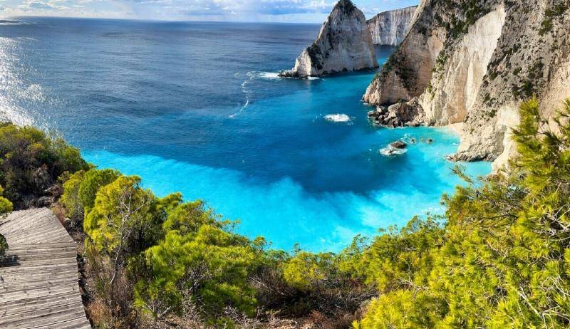 Atemberaubende Bucht mit leuchtend türkisfarbenem Wasser, umgeben von hohen weißen Klippen und üppiger Vegetation.