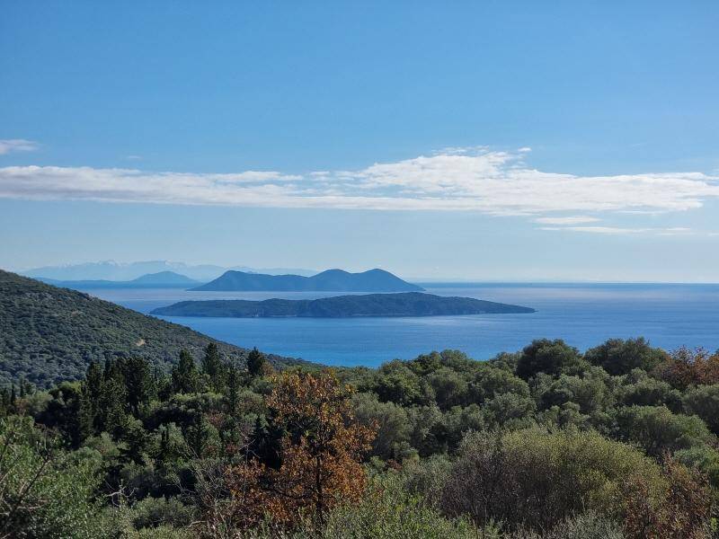 Weitläufiger Blick über das glitzernde Meer mit mehreren Inseln und üppiger Vegetation im Vordergrund.