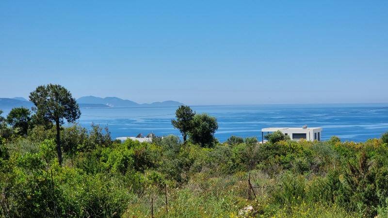 Weitläufige Aussicht auf das Meer und die Berge, umgeben von üppiger grüner Vegetation und einem modernen Haus.