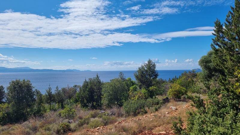 Weitläufiger Ausblick auf das glitzernde Meer und die bergige Landschaft, umgeben von mediterraner Vegetation.