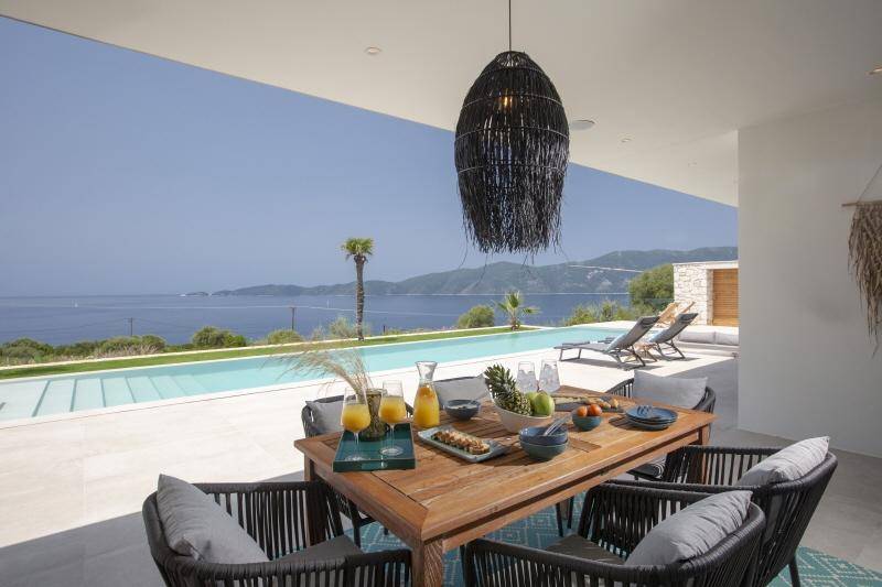 Einladender Essbereich auf der Terrasse mit gedecktem Tisch und Panoramablick auf Pool und Meer.