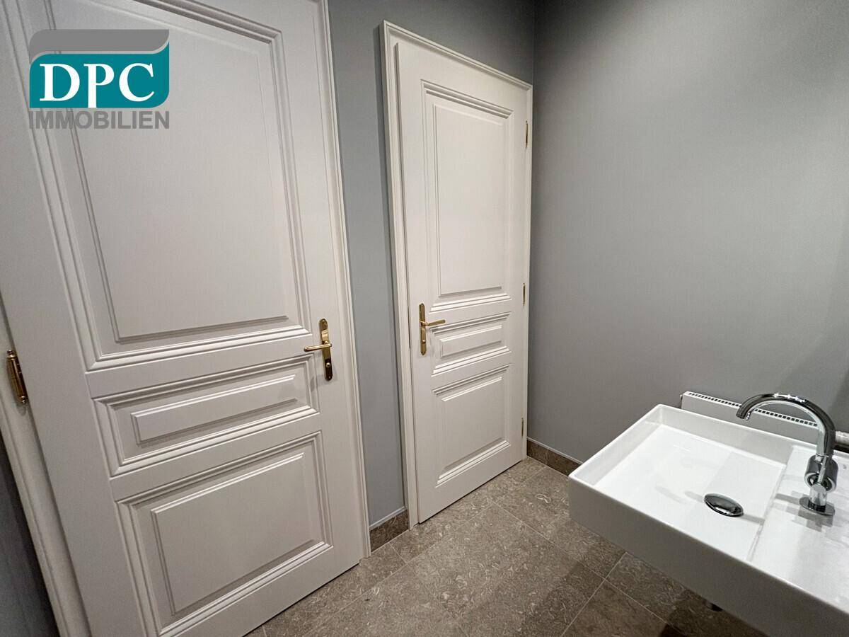 Kleiner Waschraum mit modernem Waschbecken und zwei klassischen Türen in grauem Ambiente.