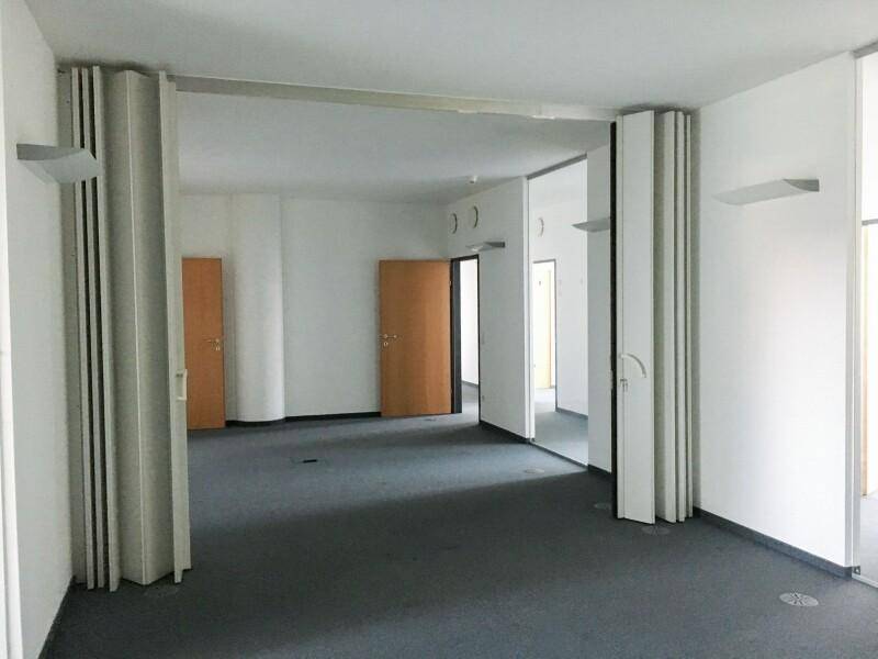 Geräumiger Bürobereich mit flexiblen Trennwänden, hellen Wänden und einem dunklen Teppichboden, bereit zur individuellen Gestaltung.