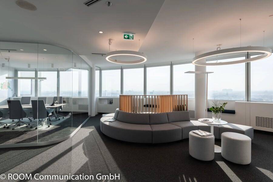 Offener Bürobereich mit flexiblen Sitzgelegenheiten, Glaswänden und weitem Ausblick.