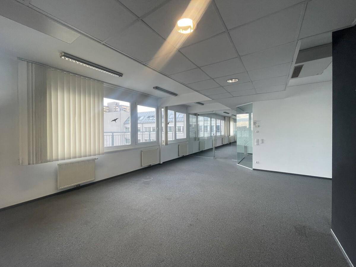Großes, leeres Büro mit Teppichboden, vielen Fenstern und Jalousien, bereit zur Einrichtung.