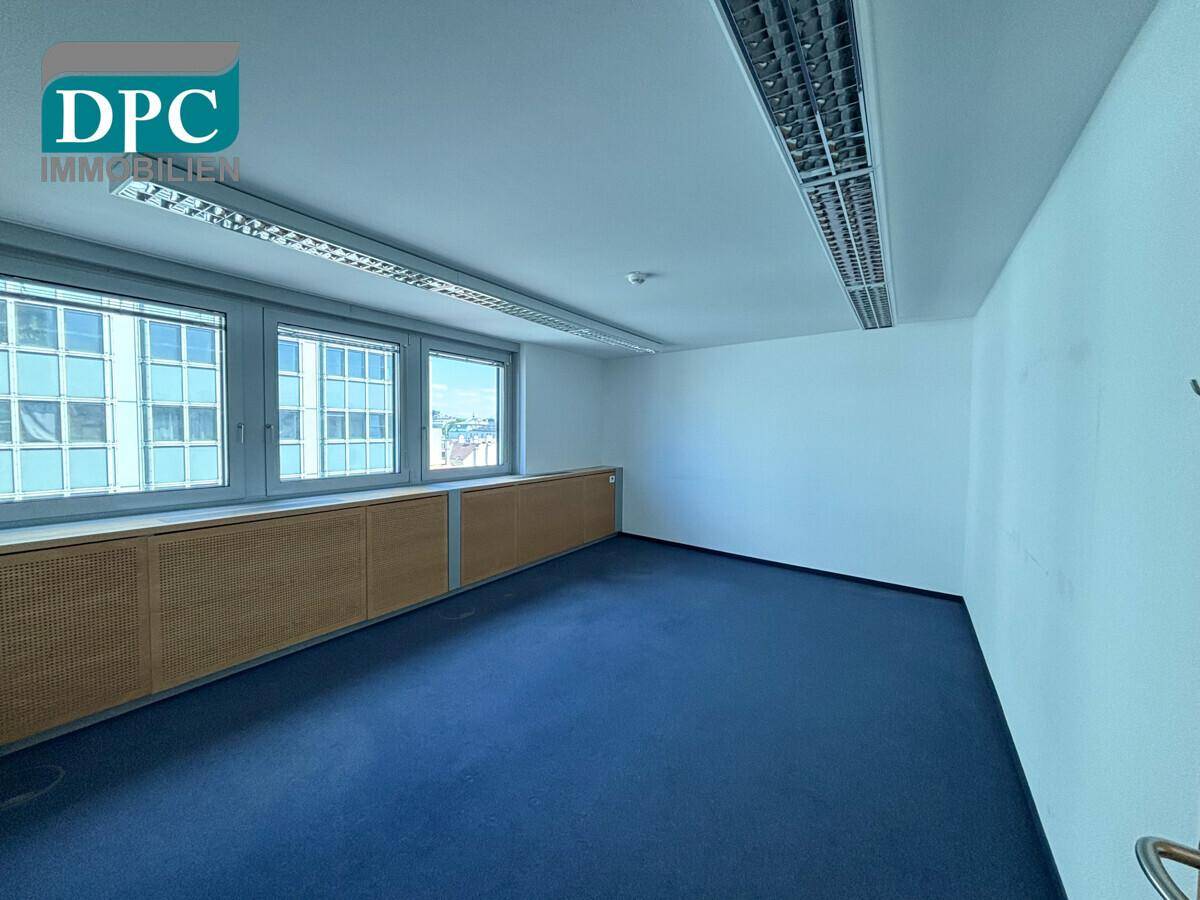 Leeres Büro mit blauem Teppichboden und einer Reihe von Fenstern, bereit für die individuelle Gestaltung.
