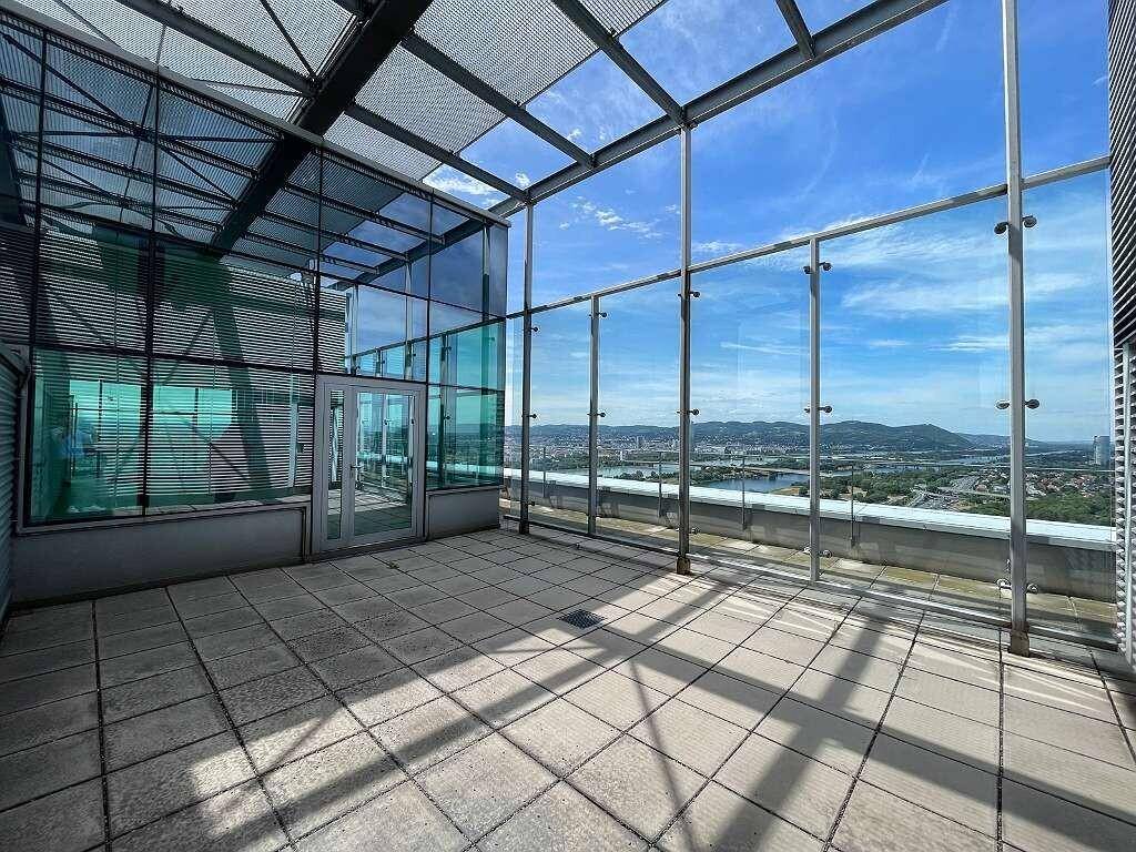 Geräumige Dachterrasse mit Glasgeländer und weitem Blick über die Stadt und den Fluss, ideal für Entspannung.