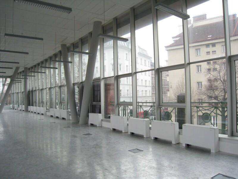Heller, langer Flur oder offener Bürobereich mit großen Fenstern und Blick auf die Stadt.
