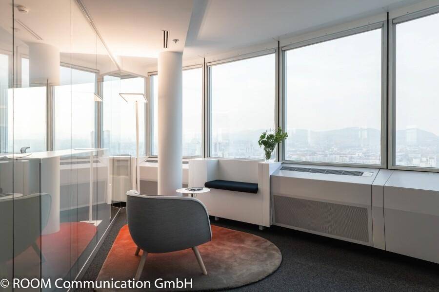 Gemütlicher Sitzbereich im Büro mit Panoramablick durch große Fenster.