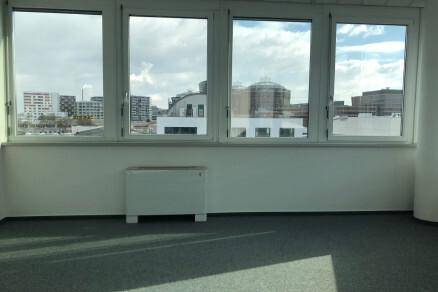 Langer Fensterbereich im Büro mit Heizkörper und Panoramablick auf die umliegenden Gebäude.