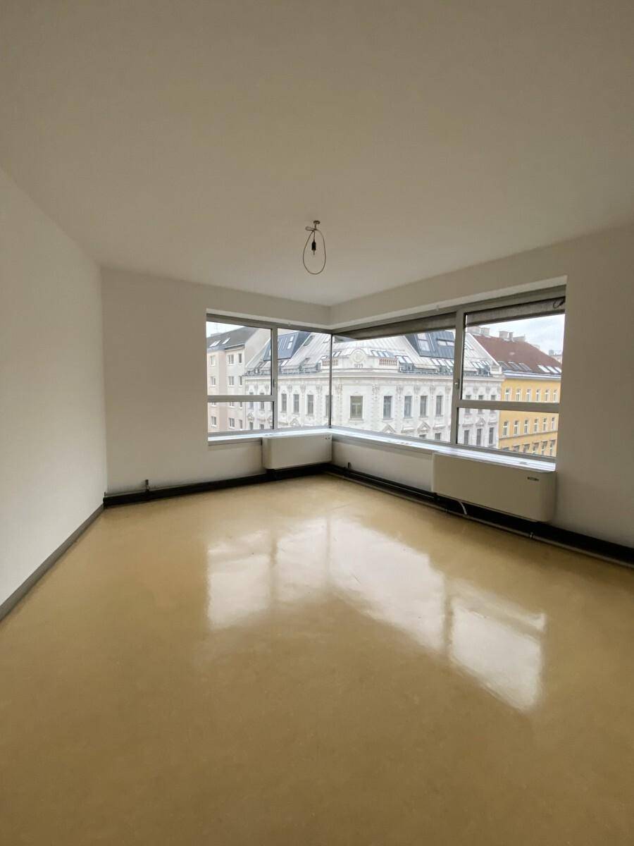 Eckbüro mit großen Fenstern und glänzendem Boden, bietet viel natürliches Licht und Stadtblick.