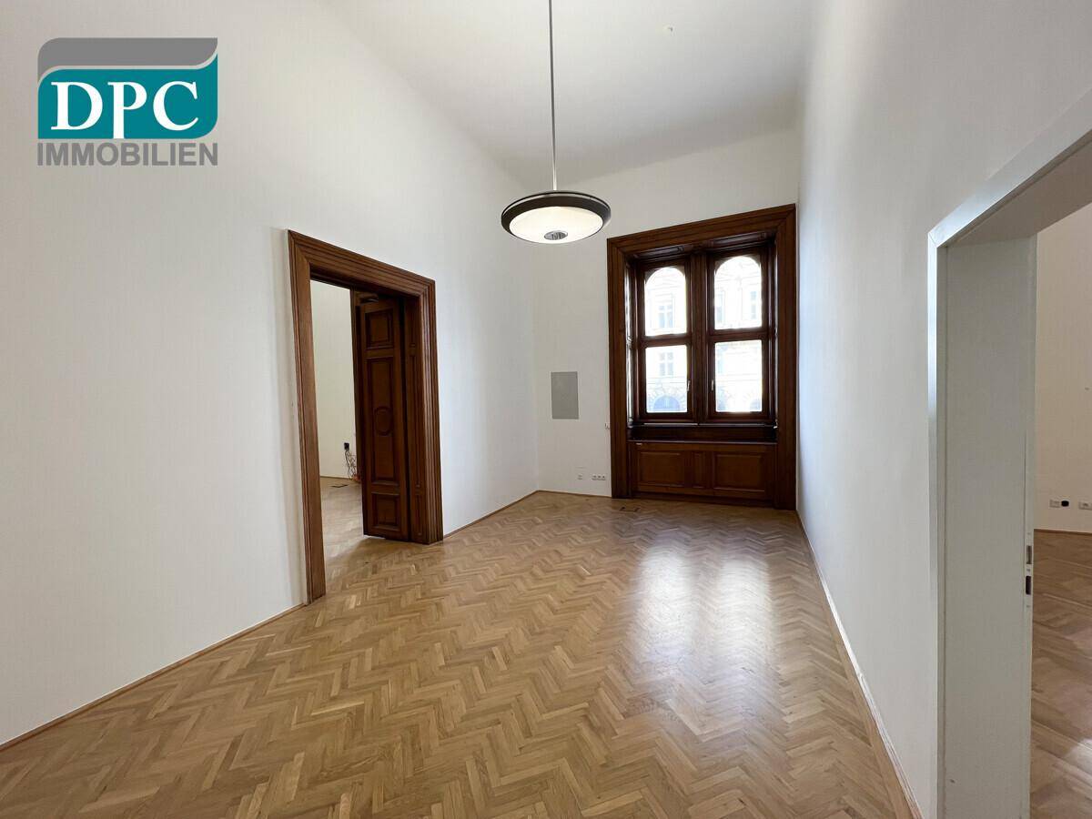 Heller Raum mit klassischem Fischgrätparkett und Holztüren, ideal für Wohn- oder Bürozwecke.