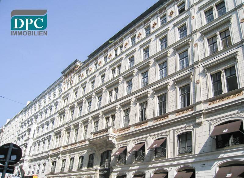 Elegante historische Fassade eines Mehrfamilienhauses mit vielen Fenstern und Markisen im Erdgeschoss.