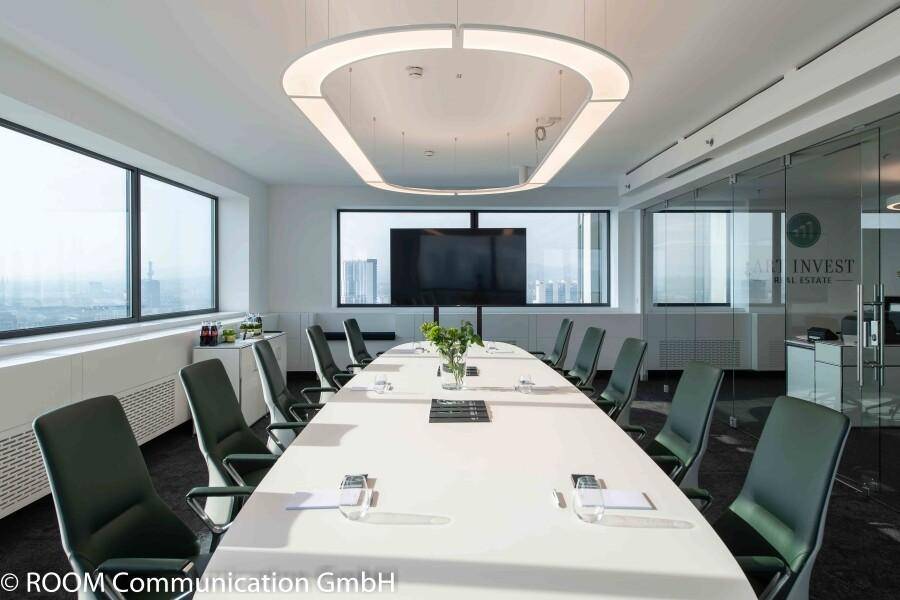 Moderner Konferenzraum mit großem Tisch, bequemen Stühlen und Panoramablick durch die Fenster.