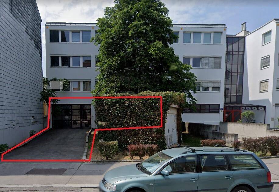 Gebäudeansicht von der Straße mit markiertem Eingangsbereich und parkendem Auto davor.