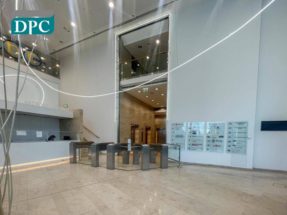 Moderne Lobby mit Sicherheitszugang, hohen Decken und Aufzügen im Hintergrund, die ein professionelles Ambiente schafft.