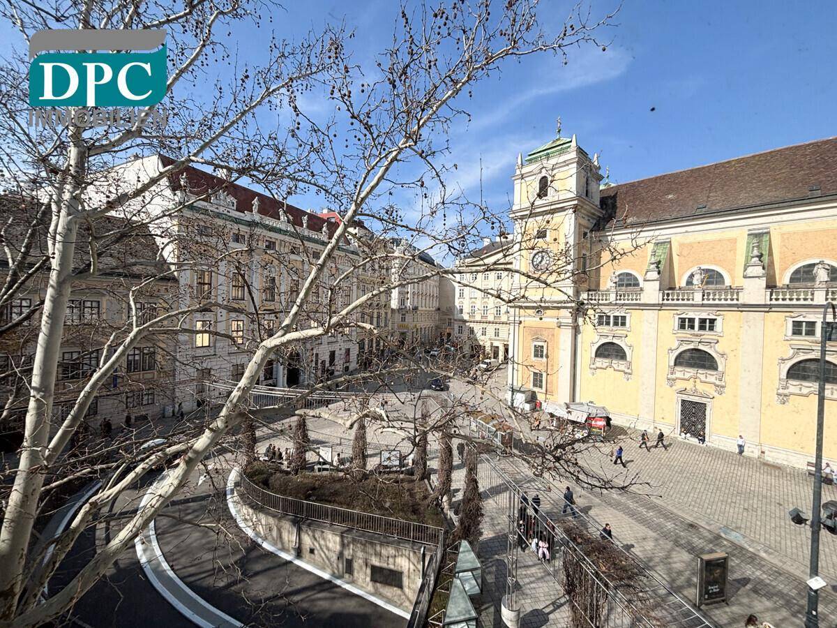 Historische Stadtansicht mit imposanten Gebäuden und einem belebten Platz unter blauem Himmel.